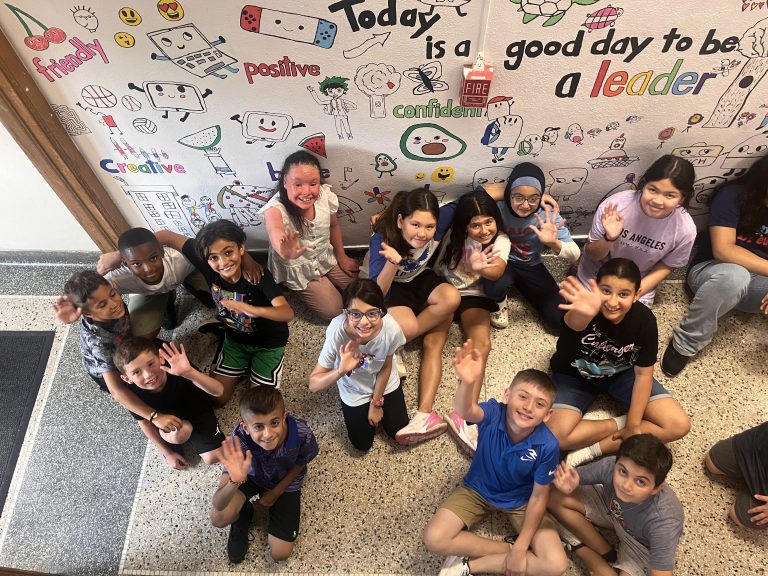 Students in the Lindbergh Elementary Summer Discovery Program sit in front of a mural they are creating in 2024.